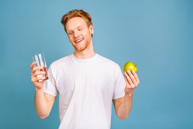 Diätkonzept und gesunder Lebensstil. fröhlicher schöner junger Mann, der Apfel isst und ein Wasser trinkt