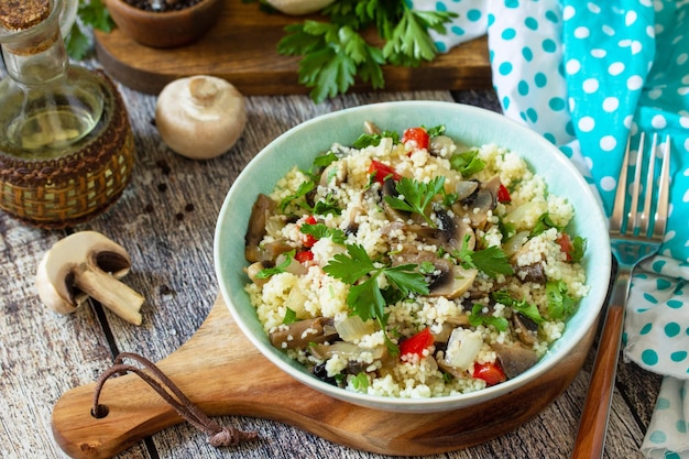 Diätkost veganes Konzept Veganer Salat mit Couscous und Champignons auf einem Holztisch