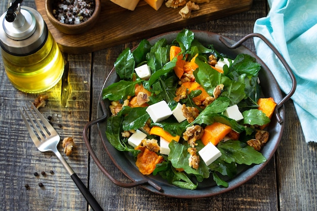 Diätmenü Veganes Essen Gesunder Salat mit gebackenem Kürbis-Feta-Käse auf einem rustikalen Holztisch