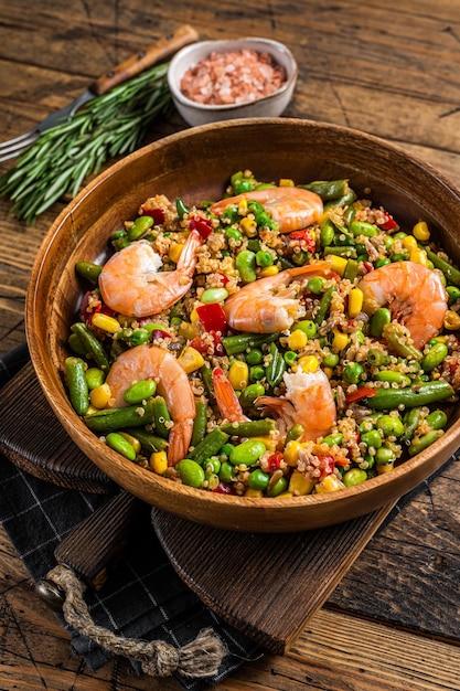 Diätmenü, veganes Essen. Gesunder Salat mit Quinoa, Gemüse und Shrimps Garnelen. Hölzerner Hintergrund. Ansicht von oben.