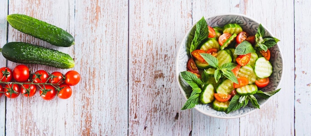 Diätsalat aus Gurken, Tomaten und Minze in einer Schüssel auf dem Webbanner der Tischplatte