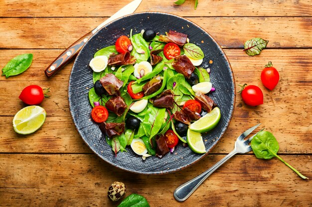 Diätsalat aus Mangold, Wachteleiern, Tomaten und Trockenfleisch. Salat mit Schinken und Gemüse.