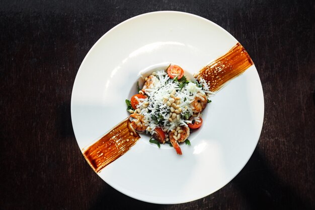 Diätsalat mit Tomaten, Garnelen, Spinat und Pinienkernen. Ansicht von oben. Flach liegen.