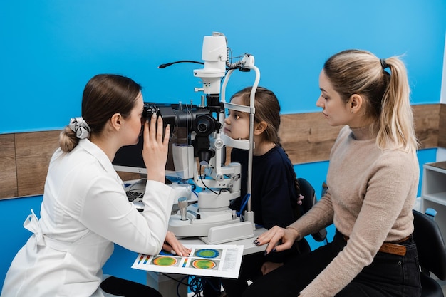 Diagnóstico da lâmpada de fenda e exame da córnea e dos olhos da criança oftalmologista pediátrico com lâmpada de fenda examina e consulta a mãe com seu filho