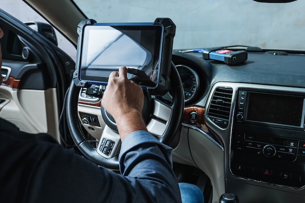 Diagnóstico do carro. inspeção técnica, eletrônica automotiva. um homem latino segura um dispositivo de digitalização.