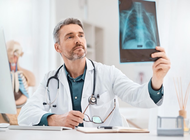 Diagnóstico y tratamiento de la lesión Disparo de un médico maduro que analiza exploraciones de rayos X en un consultorio médico