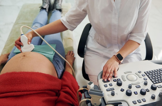 Foto diagnóstico por ultrasonido la mujer embarazada está en la clínica en el gabinete y tiene un control de salud