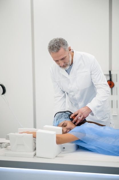 Foto diagnósticos médico masculino maduro preparando um paciente para investigação de ressonância magnética