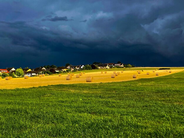 Foto diagonale linien und heuballen auf dem ländlichen deutschland dunkler himmel vor einem gewitter ein feld mit