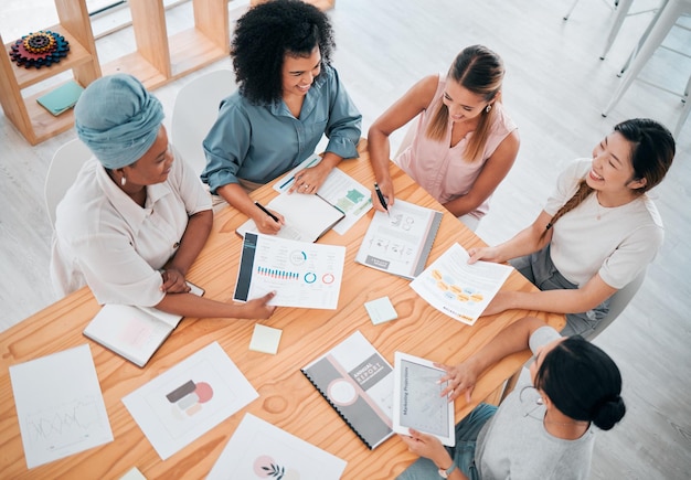 Foto diagrammdokumente und geschäftliche teamarbeit in einem meeting mit einer gruppe von arbeitern, die von oben am bürotisch sitzen strategieanalyse und zusammenarbeit des finanzteams, das an einem datenanalyseprojekt arbeitet