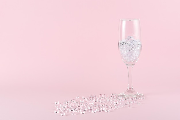 Diamantes e copo de vinho em fundo rosa conceito criativo de festa mínima