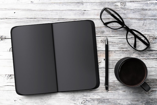 Diario en blanco negro taza de café y vasos en una mesa de madera