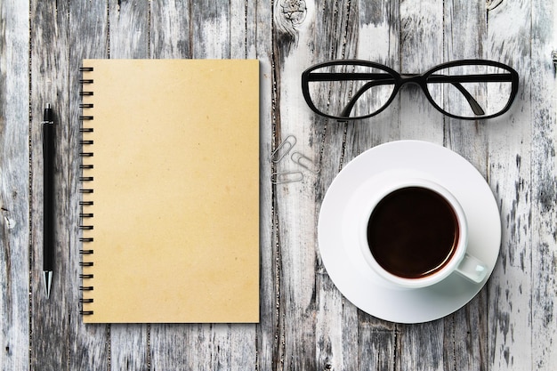 Diario en blanco y taza de café en una maqueta de mesa de madera vintage