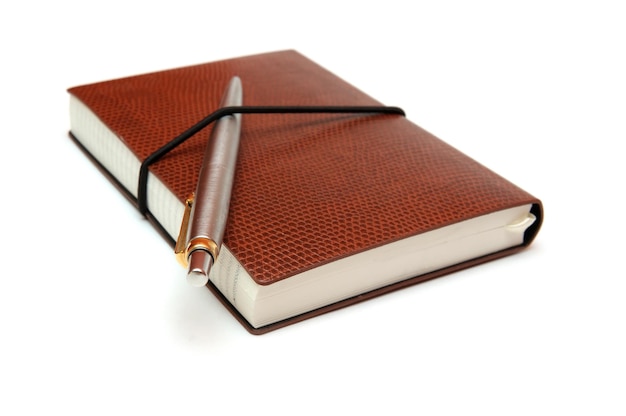 Un diario de cuero marrón con un bolígrafo en la parte superior.