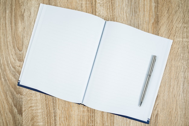 Foto diário de caderno em branco com caneta prata na mesa de madeira