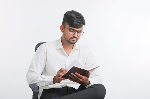 Diario de lectura masculino indio joven sobre fondo blanco.