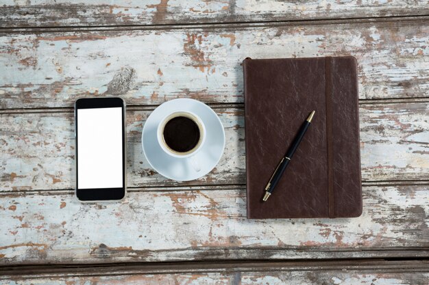 Diario, teléfono inteligente y bolígrafo con taza de café