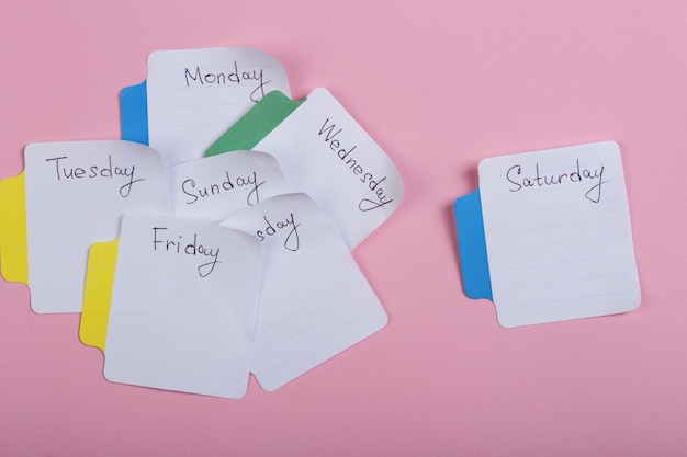 Los días de la semana las pegatinas de papel unidas al fondo rosa.