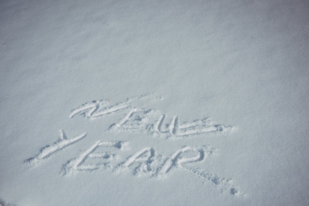 Dibujando en la nieve, palabras escritas por una mano humana. Concepto de año nuevo.