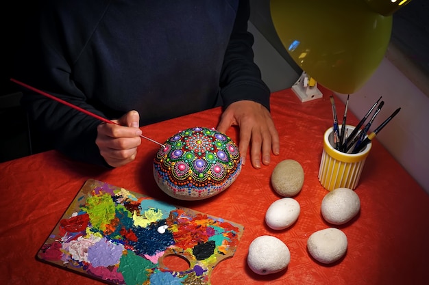 Dibujando con un pincel un mandala sobre una piedra