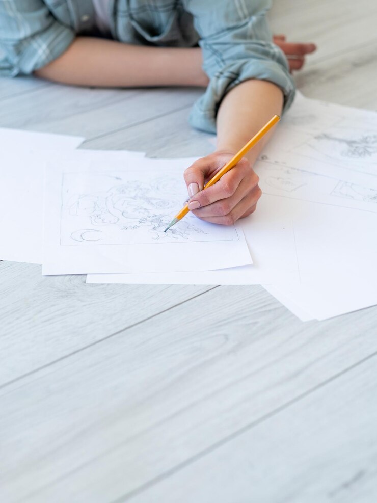 Foto dibujo arte pasatiempo creativo diseño gráfico habilidad artesanal artista zurda dibujando con lápiz sobre papel blanco sobre una superficie de textura de madera clara