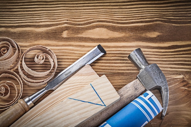 Dibujo de construcción azul martillo de orejas cincel más firme virutas de madera sobre tablero de madera vintage.