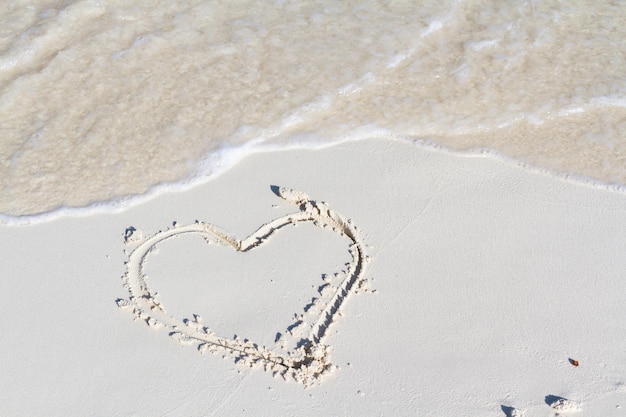 Dibujo de corazón en la playa con onda.