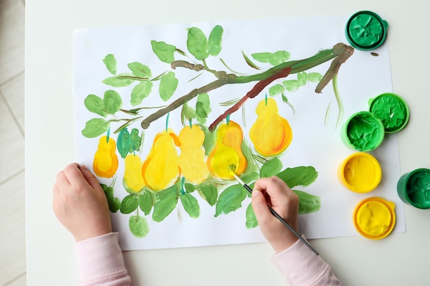 Dibujo infantil con pinturas limones en un árbol.