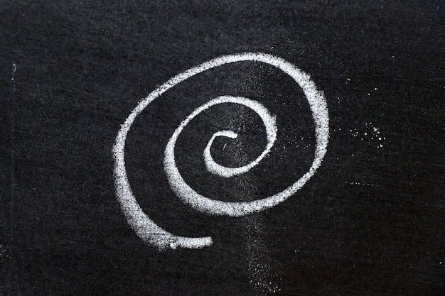 Dibujo a mano con tiza de color blanco como forma de espiral sobre fondo de tablero negro