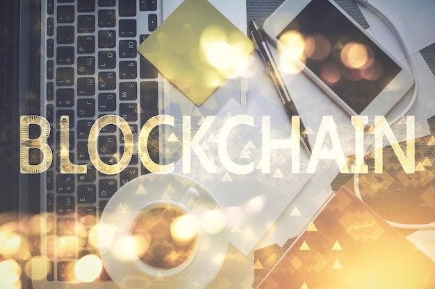 Dibujos de hologramas del tema Blockchain sobre la computadora en el fondo del escritorio Vista superior Concepto de exposición múltiple de criptoeconomía