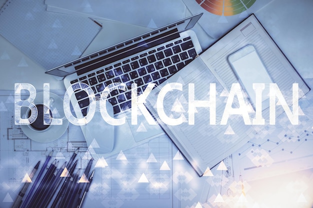 Dibujos de hologramas del tema Blockchain sobre la computadora en el fondo del escritorio Vista superior Concepto de exposición múltiple de criptoeconomía