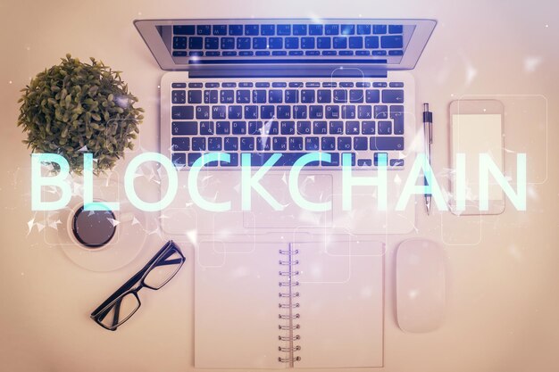 Dibujos de hologramas del tema Blockchain sobre la computadora en el fondo del escritorio Vista superior Concepto de exposición múltiple de criptoeconomía