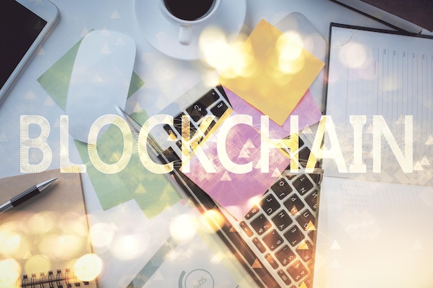 Dibujos de hologramas del tema Blockchain sobre la computadora en el fondo del escritorio Vista superior Concepto de exposición múltiple de criptoeconomía