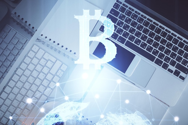 Dibujos de hologramas del tema Blockchain sobre la computadora en el fondo del escritorio Vista superior Doble exposición