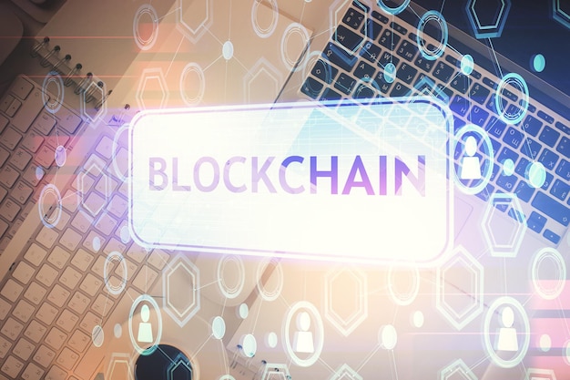 Dibujos de hologramas del tema Blockchain sobre la computadora en el fondo del escritorio Vista superior Doble exposición