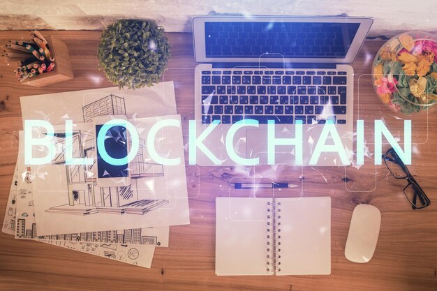 Dibujos de hologramas del tema Blockchain sobre la computadora en el fondo del escritorio Vista superior Doble exposición