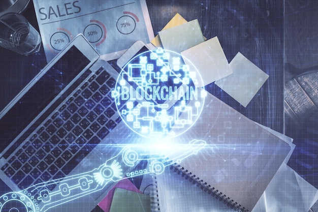 Dibujos de hologramas del tema Blockchain sobre la computadora en el fondo del escritorio Vista superior Doble exposición