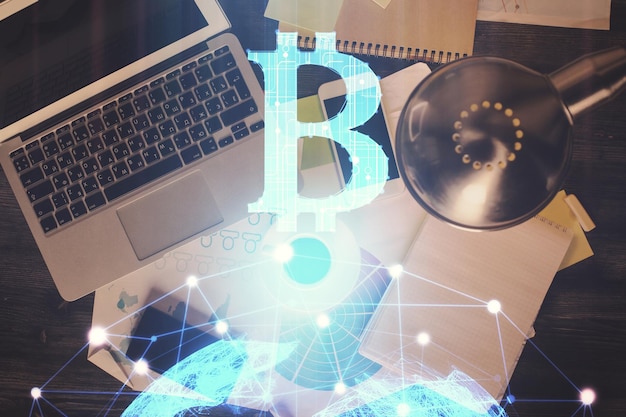 Dibujos de hologramas del tema Blockchain sobre la computadora en el fondo del escritorio Vista superior Doble exposición