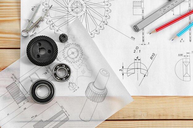 Foto dibujos de ingeniería de piezas con herramientas en mesa de madera.