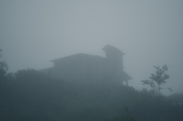 Foto dichte wolken in dem kleinen haus auf einem berggipfel. nebeliger morgen und die silhouette eines süßen zuhauses