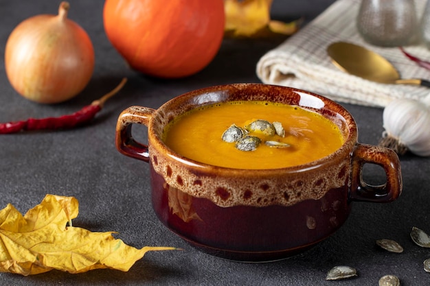 Dicke Kürbiscremesuppe mit Kürbiskernen in einer Schüssel auf dunkelgrauem Hintergrund