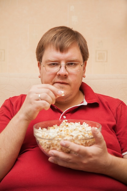 Dicker Mann beim Fernsehen Popcorn essen