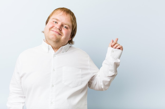 Dicker mann der jungen authentischen rothaarigen, der mit dem zeigefinger weg freundlich zeigend lächelt.