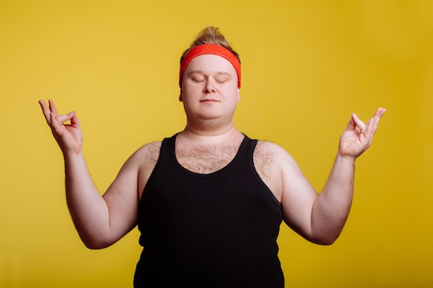 Dicker Mann, der mit Meditation auf gelber Wand entspannt