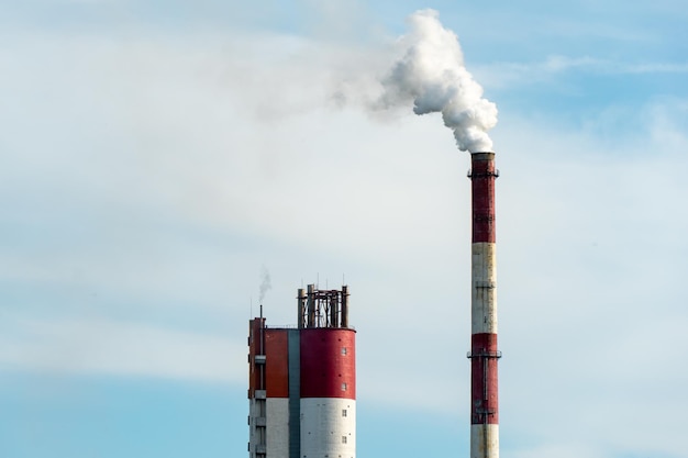 Dicker weißer Rauch aus einem großen Rohr einer Industrieanlage oder Fabrik Ein rauchender Schornstein vor blauem Himmel Umweltverschmutzung durch chemische und pharmazeutische Unternehmen