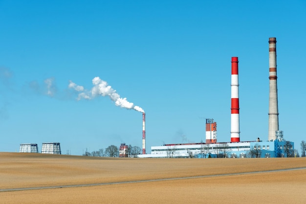 Dicker weißer Rauch aus einem großen Rohr einer Industrieanlage oder Fabrik Ein rauchender Schornstein vor blauem Himmel Umweltverschmutzung durch chemische und pharmazeutische Unternehmen