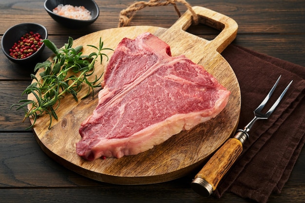 Dickes Raw TBone Steak Dryaged Raw Tbone oder Porterhouse Beefsteak mit Kräutern und Salz auf dunklem Hintergrund Selektiver Fokus und Kopierbereich
