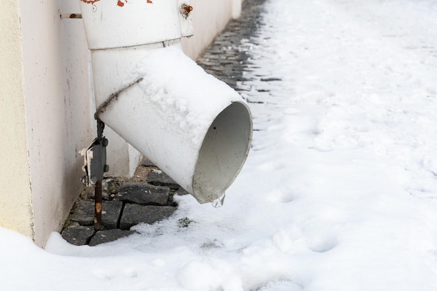 Die Abflussrohre sind mit Eis und Schnee bedeckt Nach einem heftigen Schneesturm ist die Stadt mit Schnee und Eis bedeckt. An der Fassade des Gebäudes Eis befinden sich viele Eiszapfen auf Bürgersteigen und Straßen