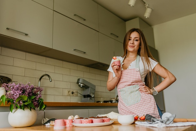 Die Aktion der Herstellung von Cupcakes aus rotem Samt Frau Hand Rohrleitungen Frischkäse auf Cupcake