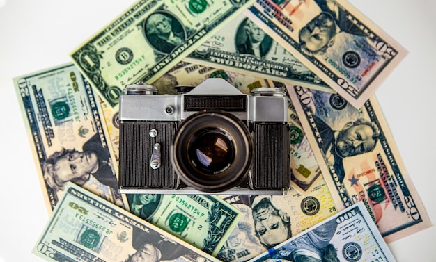 Foto die alte ruinierte analoge kamera befindet sich auf den us-dollar-bargeldscheinen. geld. kamera. fotografie